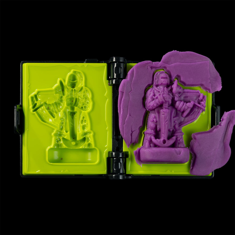 
                  
                    A spellbook shaped clay mold toy used in the Necromolds wargame to mold clay minis in the shape of creepy monsters. The clay is similar to purple play doh.
                  
                