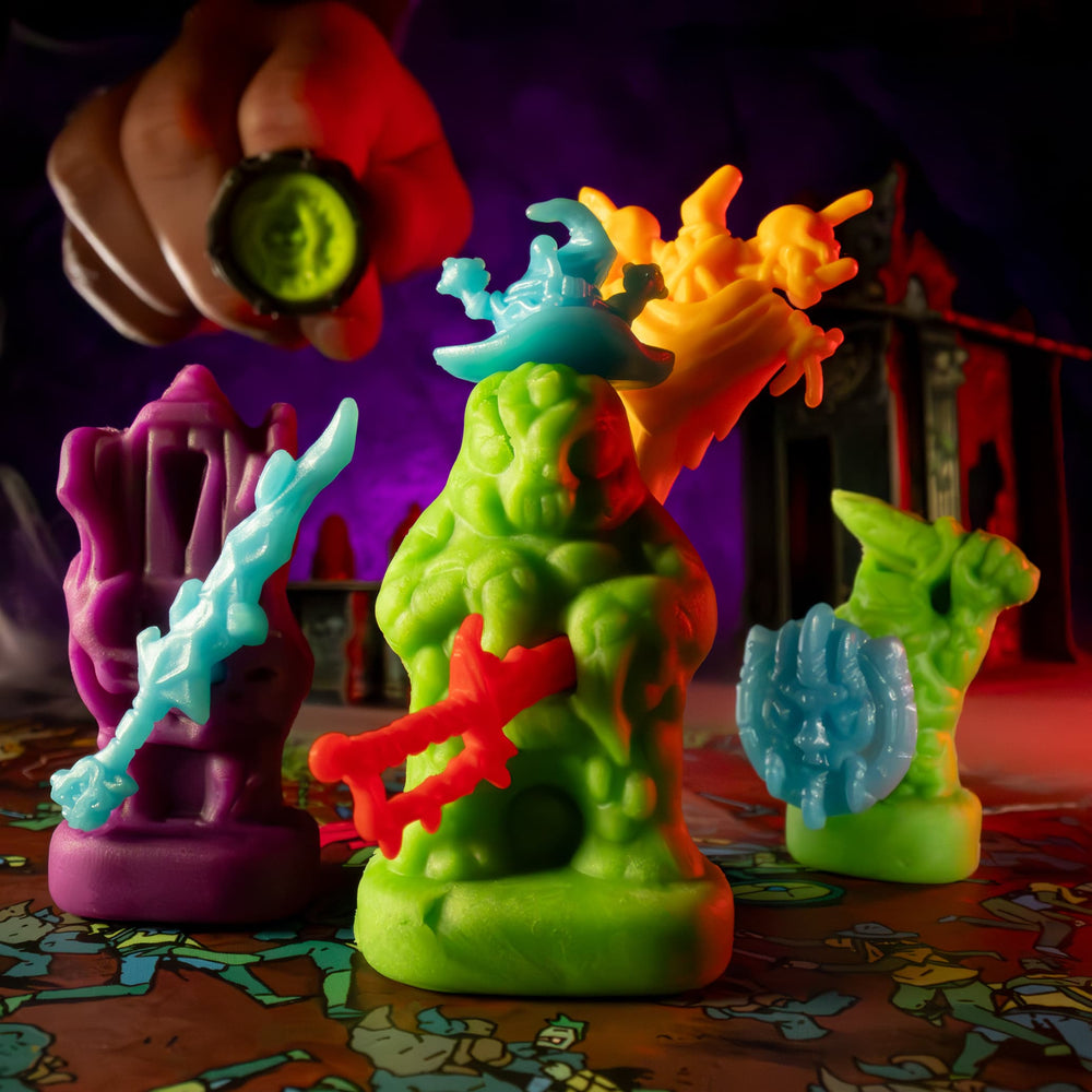 
                  
                    Clay minis of creepy monsters created from clay molds being used in the Necromolds wargame board game. The clay is similar to play doh. The player is about to smash the mini with a caster ring mold.
                  
                