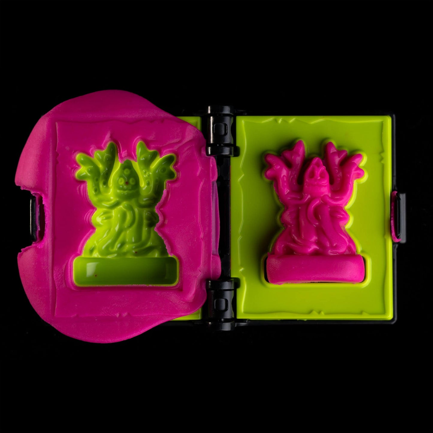 
                  
                    Spellbook-shaped clay mold toy creating an Ankropora mini from pink clay (compare to play dough) in a Necromolds board game
                  
                