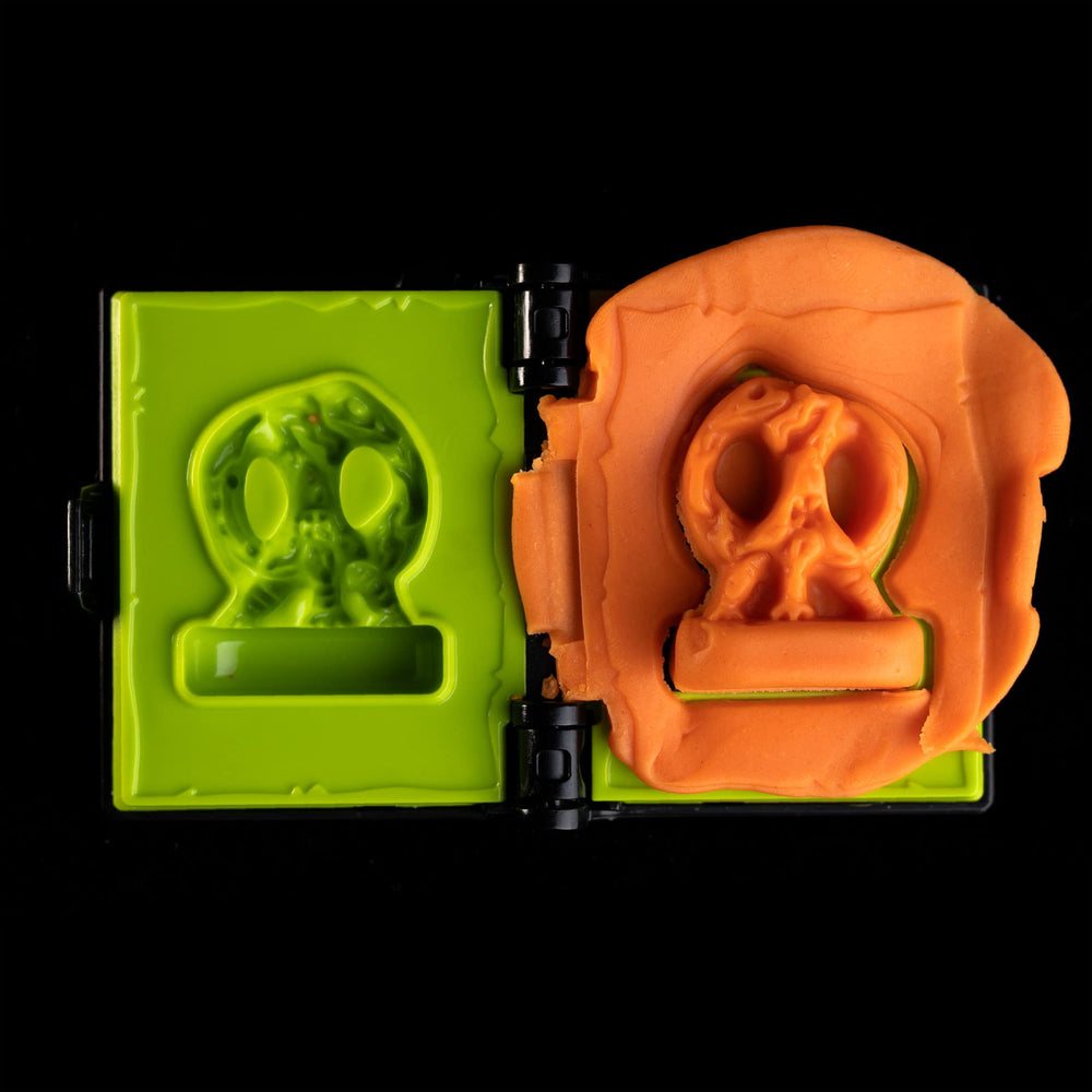 
                  
                    Spellbook-shaped clay mold toy creating a Fungix mini from orange clay (compare to play dough) in a Necromolds board game
                  
                